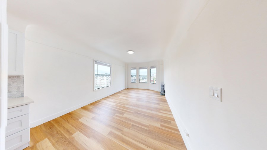 A long hallway with wooden floors and white walls.